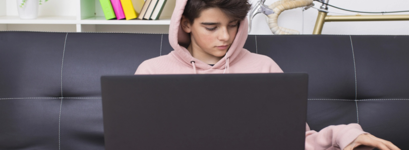 Figura masculina ce sta [e canapea, uitandu-se in laptop