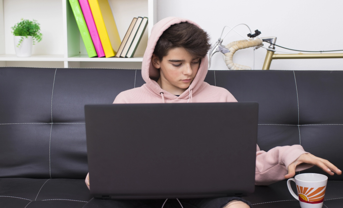 Figura masculina ce sta [e canapea, uitandu-se in laptop